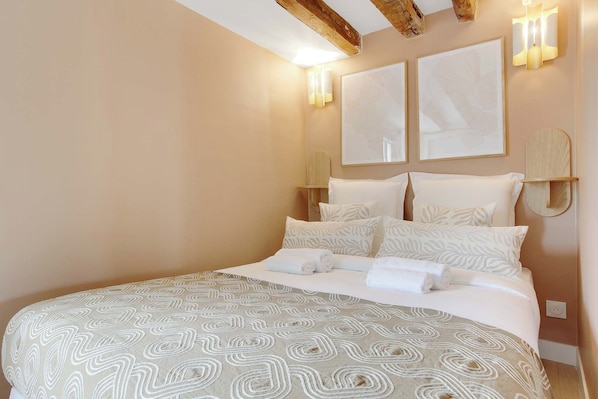 Un dormitorio con una cama grande, dos lámparas de pared y dos obras de arte enmarcadas.