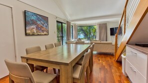 Een moderne eethoek met een houten tafel en stoelen, een bank en een televisie.