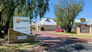 Een receptiebord voor Cape View Beach Resort, met een goed zicht op het gebouw en een rode auto op de oprit.