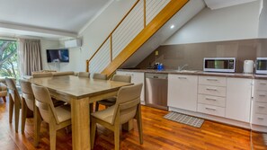 Een moderne keuken met een houten eettafel, inbouwapparatuur en een trap.