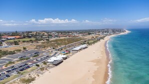 A coastal road with a beach on one side and a residential area on the other.