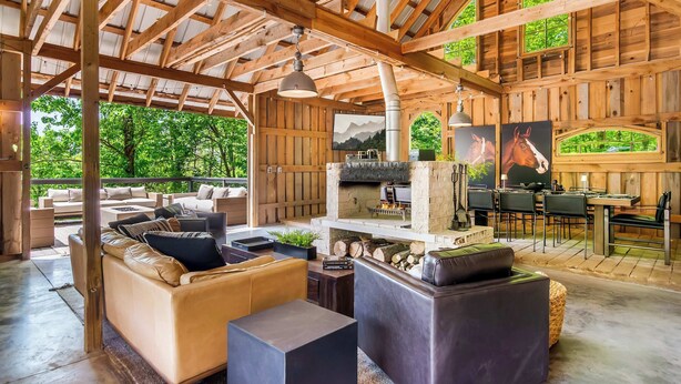 Un intérieur spacieux en bois, agrémenté d’une cheminée, d’un espace salon extérieur et d’œuvres d’art.