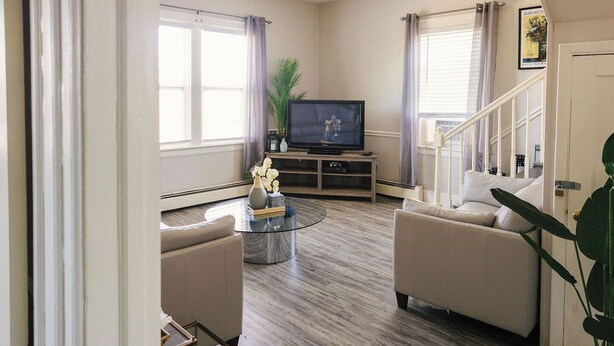 A living room with a sofa, a coffee table, a TV, and a staircase.