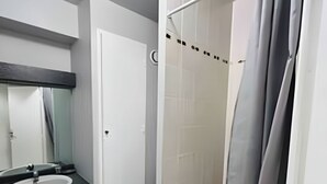 A modern bathroom with a white sink, a mirror, and a shower area with a curtain. - La Suite Buirette Hypercentre (Reims)