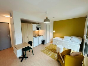 A compact living space with a kitchenette, a dining area, and a bed. - We Live In R - Suite 202 (Reims)