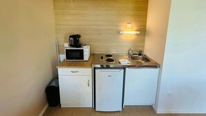 Une petite cuisine équipée d’un four à micro-ondes, d’une machine à café et d’un petit réfrigérateur.