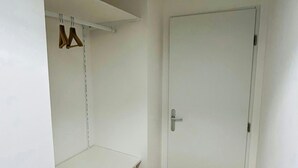 Une pièce avec une porte blanche, une étagère blanche et un plancher en bois.