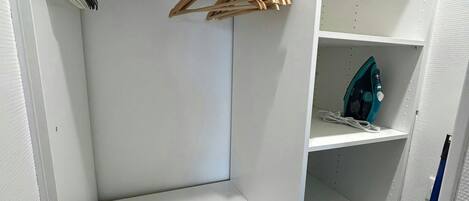 A laundry area with a washing machine, a drying rack, and shelves for storage.