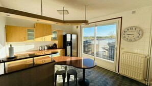 Une cuisine moderne dotée d’un grand îlot central, de meubles en bois et offrant une vue à travers la porte vitrée.