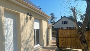 A residential property with a garage door, a wooden fence, and a tree. - "La clé des champs" Vacation Rental (Bueil)