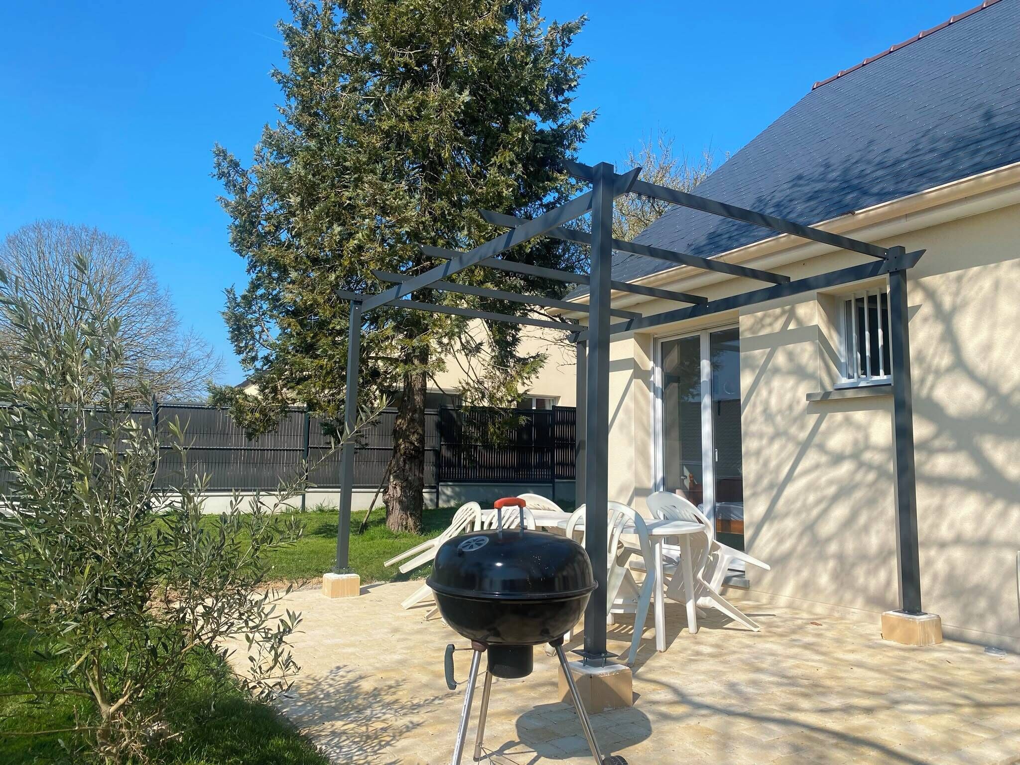 Een achtertuin met een barbecue, tuinmeubilair en een pergola.