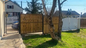 A residential property with a gated entrance, a tree, and a white fence. - "La clé des champs" Vacation Rental (Bueil)