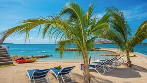 A beach with lounge chairs, a kayak, and a small pool. - Luxe Grand Villa Modern Spacious 6-bedroom with private Beach. Staff Included. (St. Ann)