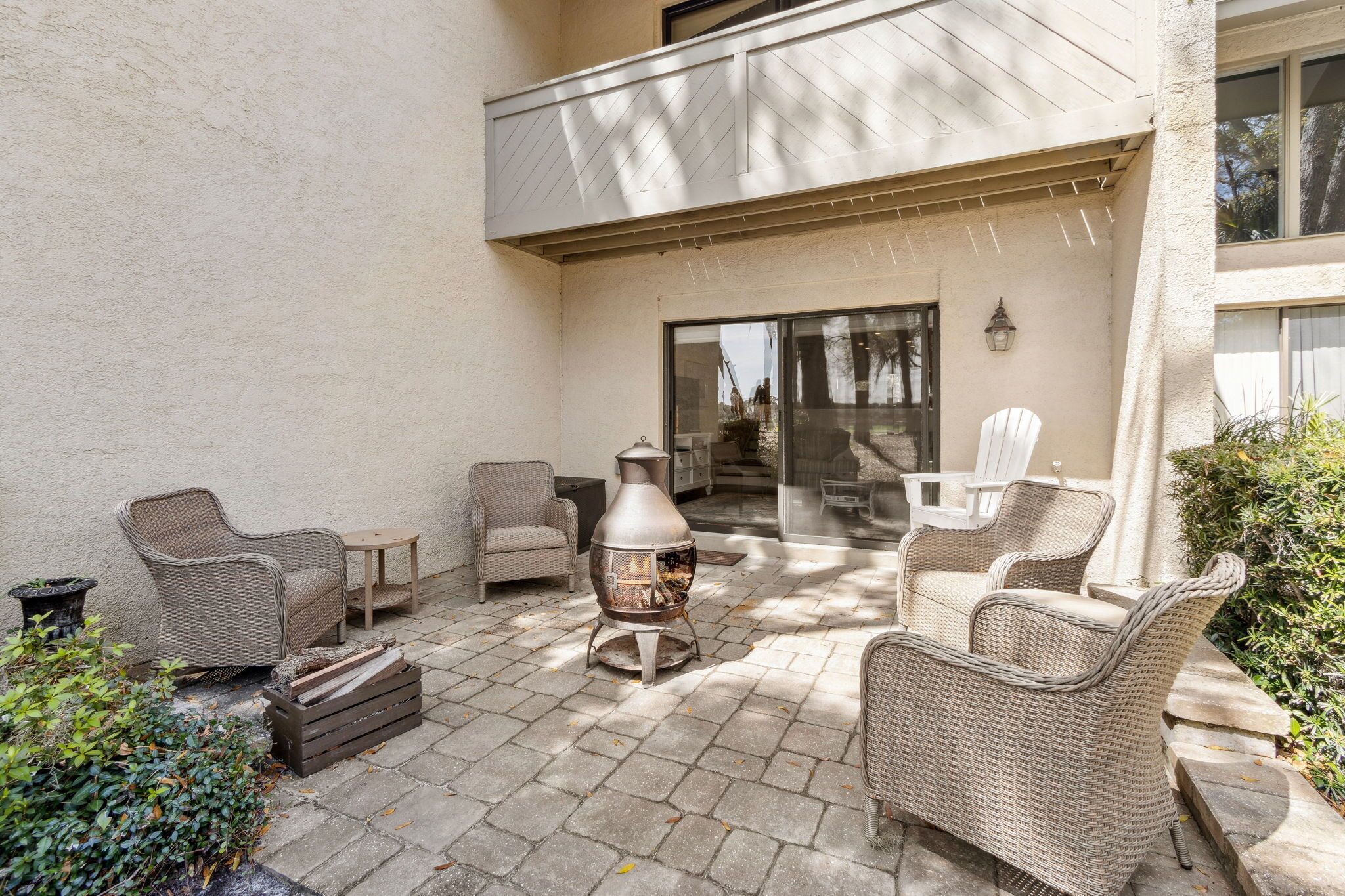 A patio with wicker furniture, a grill, and a glass door leading to a balcony.