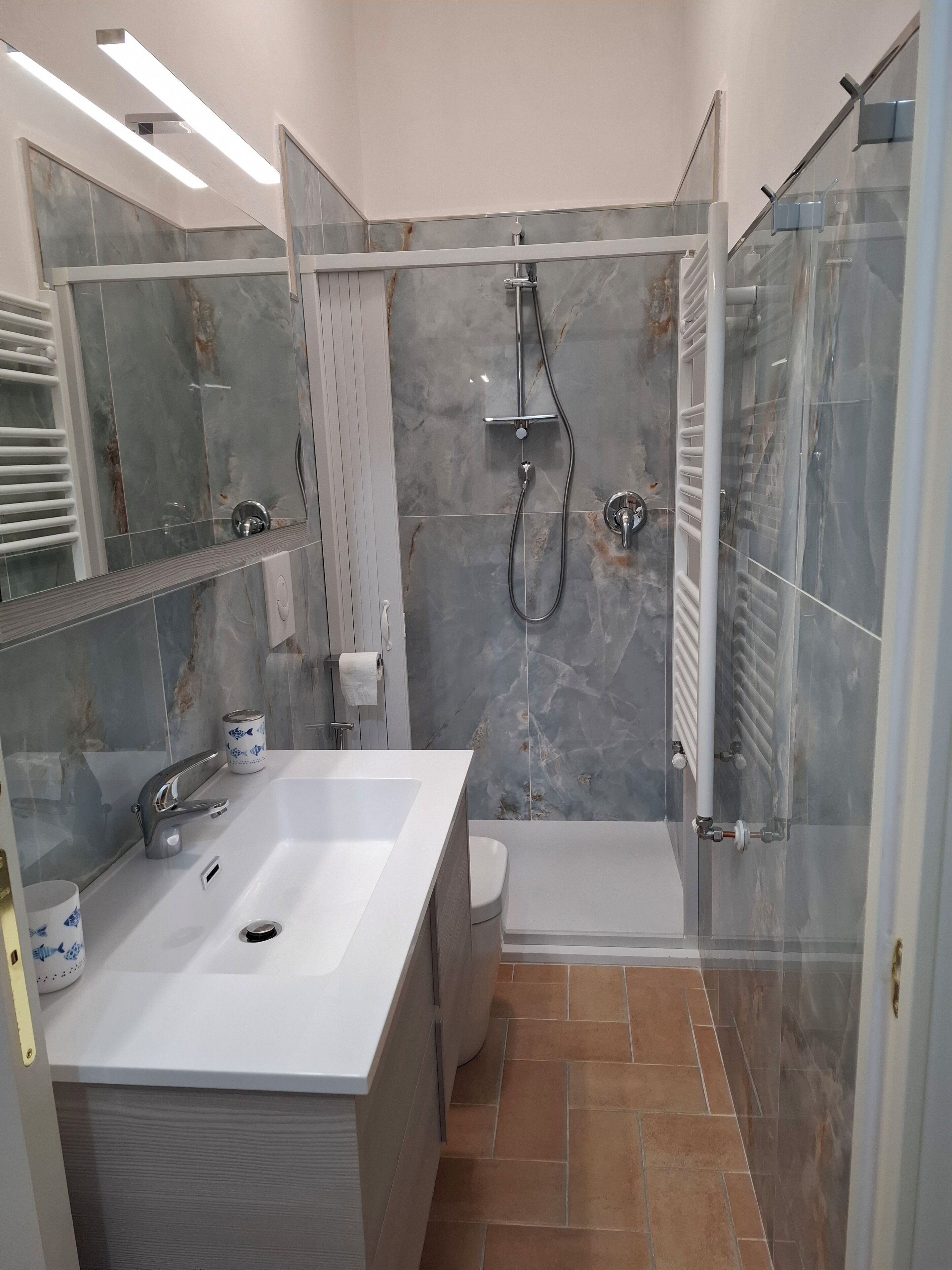 Un bagno moderno con un lavandino bianco di grandi dimensioni, un box doccia in vetro e un water.