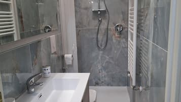 Un bagno moderno con un lavandino bianco di grandi dimensioni, un box doccia in vetro e un water.