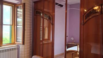 Un dormitorio con cama, armario de madera y ventana con cortinas.