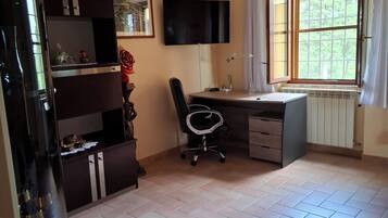 Una habitación con escritorio, silla y televisor montado en la pared.