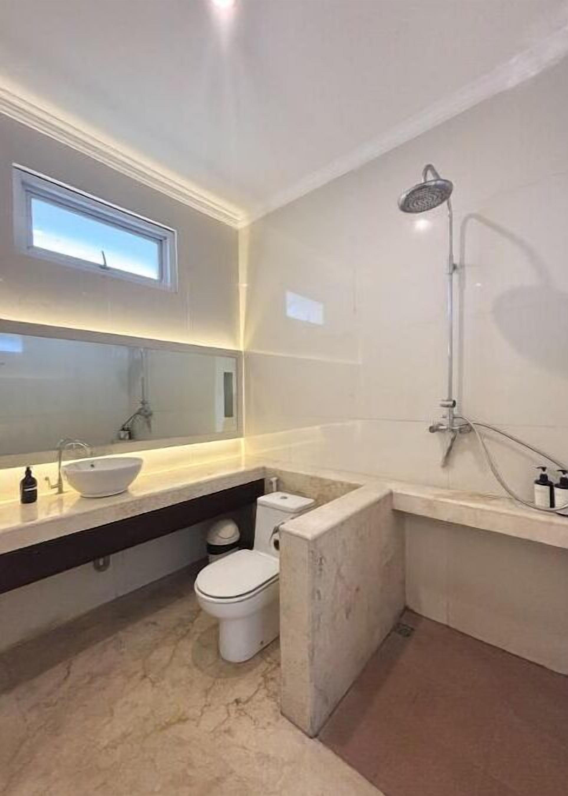 A modern bathroom with a large mirror, a vessel sink, a toilet, and a shower.