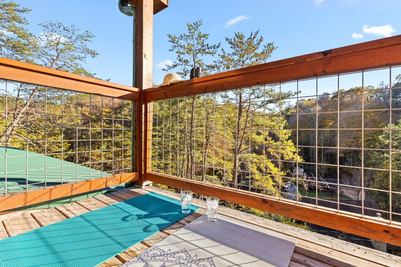 A wooden deck with a view of trees and a green roof.
