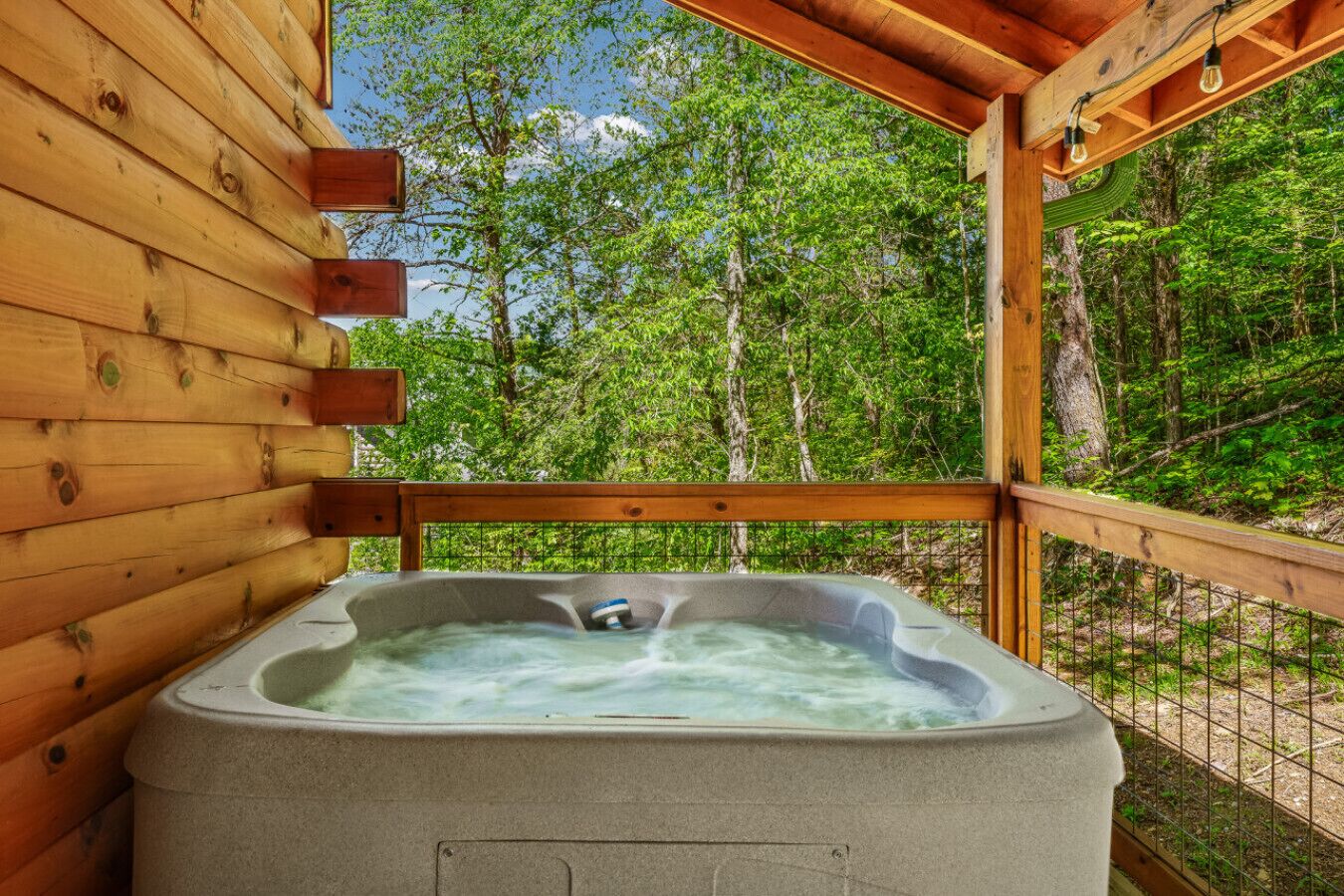 A hot tub in a wooden cabin with a view of a forest.