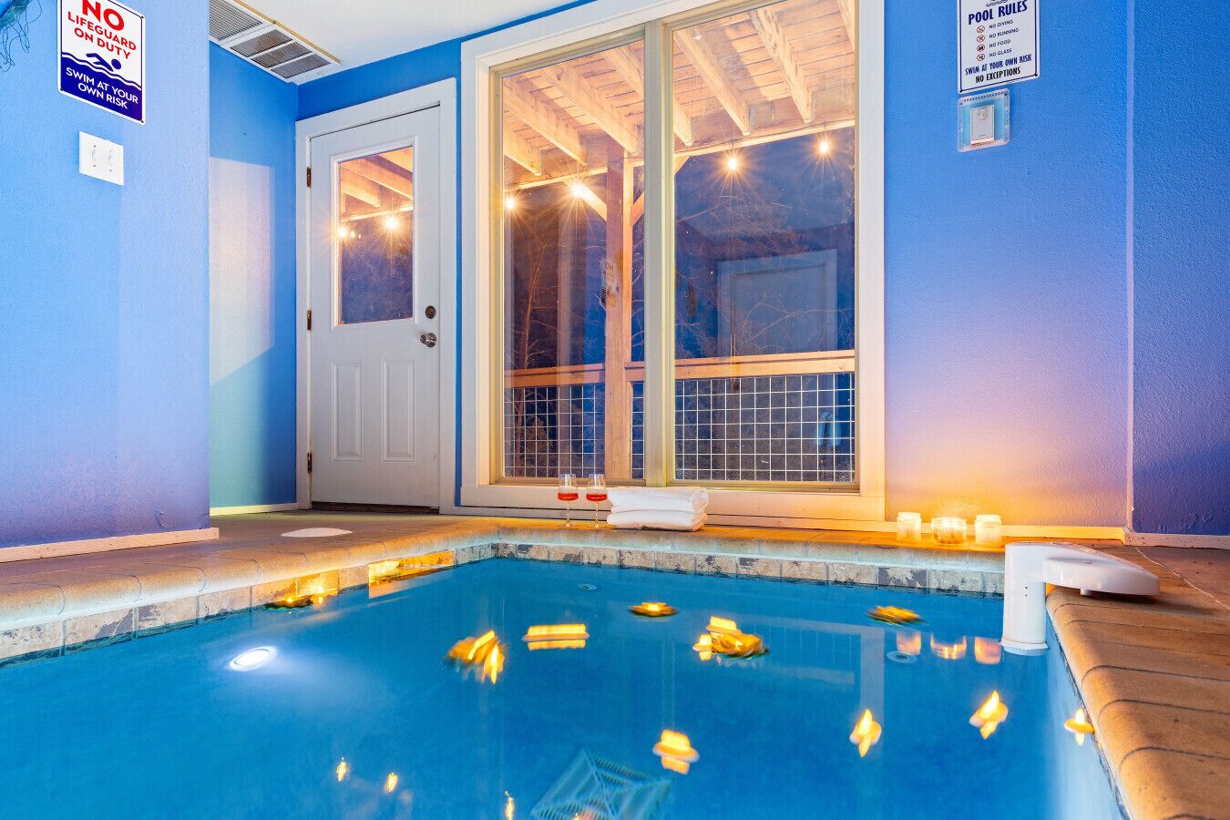 Un espace piscine avec un mur bleu, une porte blanche et une grande fenêtre. Les règles de la piscine sont affichées sur le mur.