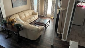 Un salon avec un canapé beige, une table basse en verre et un tableau accroché au mur.