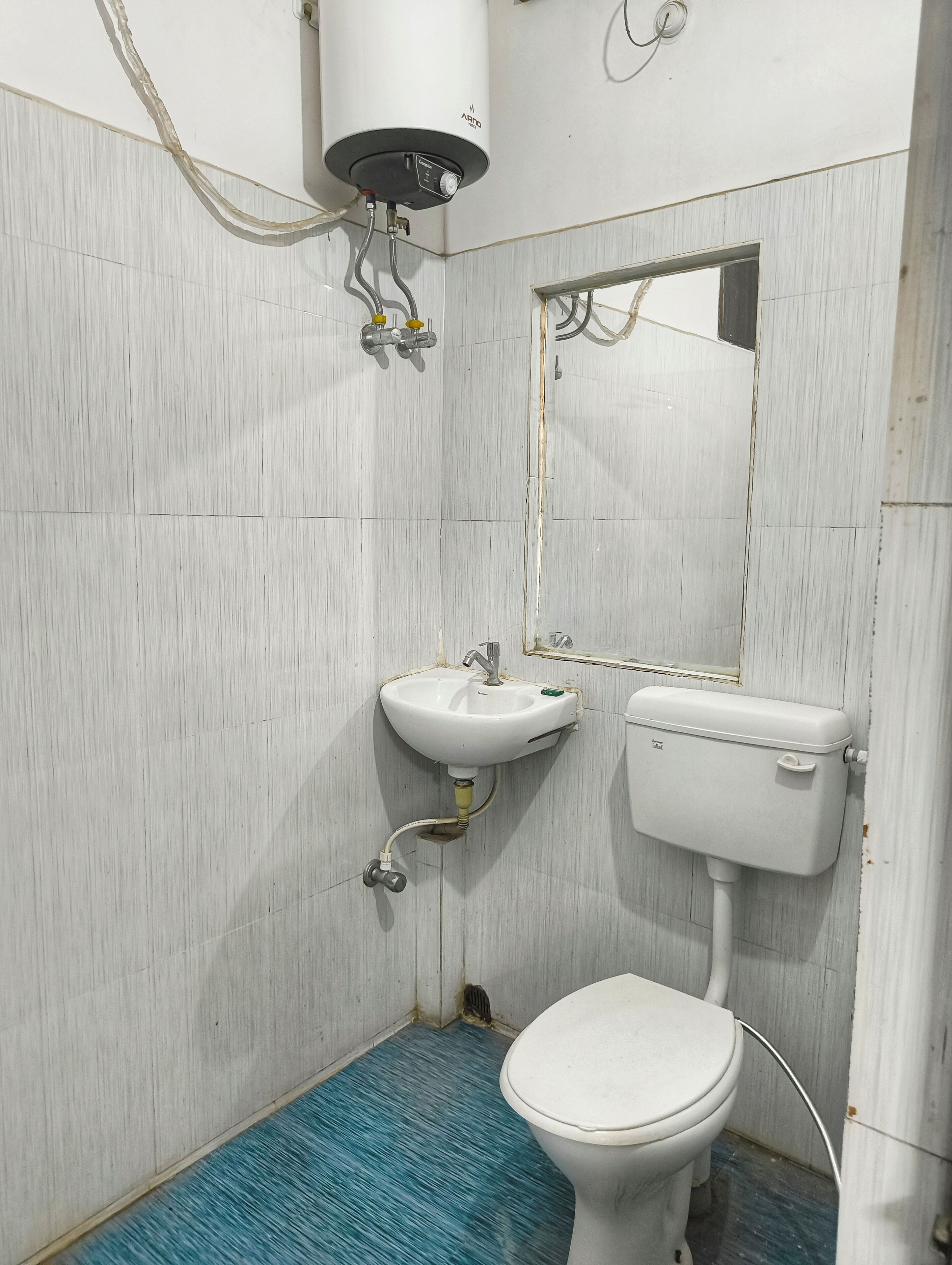 Un baño con inodoro blanco, lavabo y espejo.