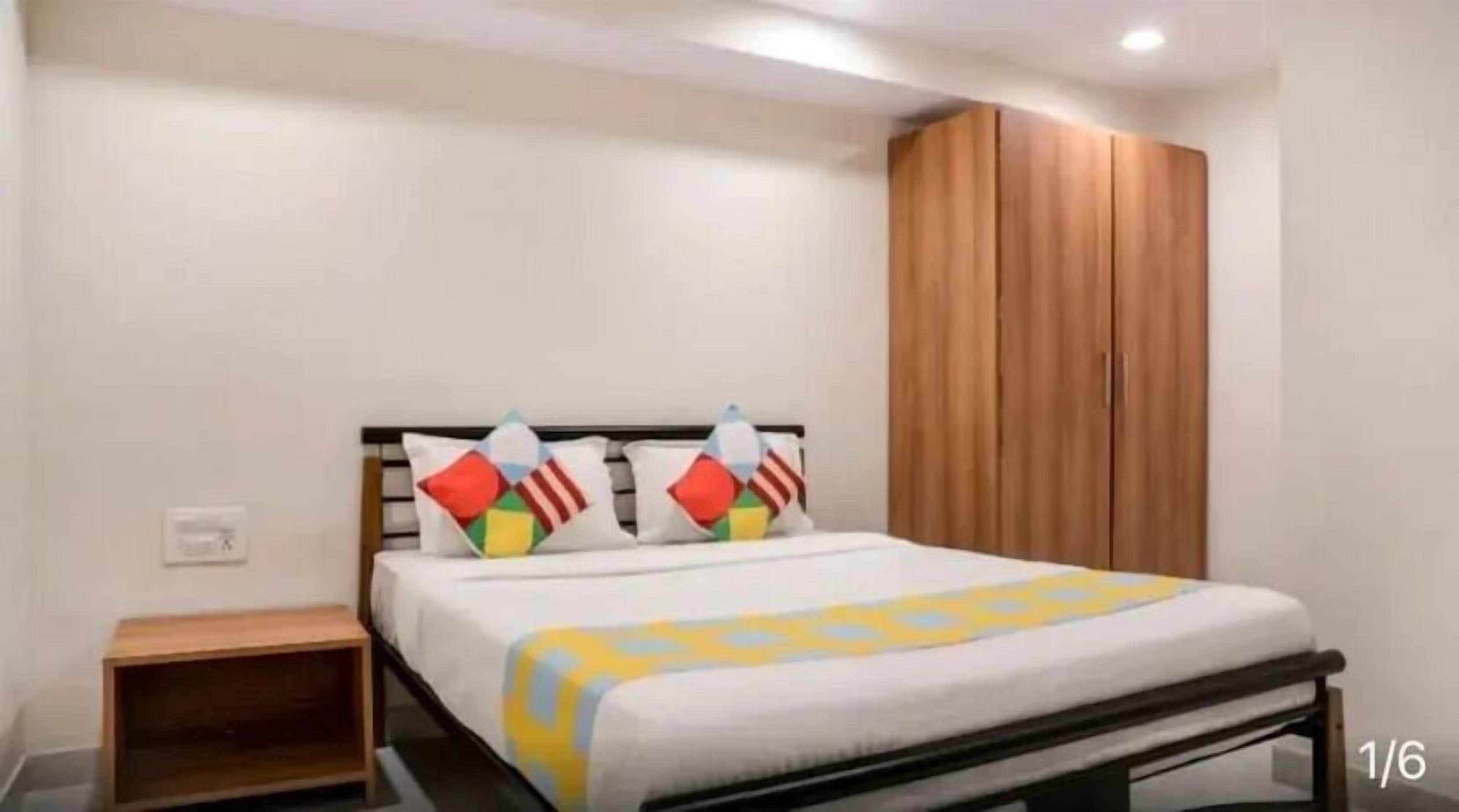 Um quarto com uma cama, um guarda-roupa de madeira e uma mesa de cabeceira.