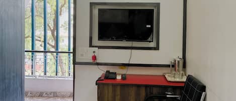 Habitación de hotel con cama, escritorio con silla, televisión montada en la pared y aire acondicionado.