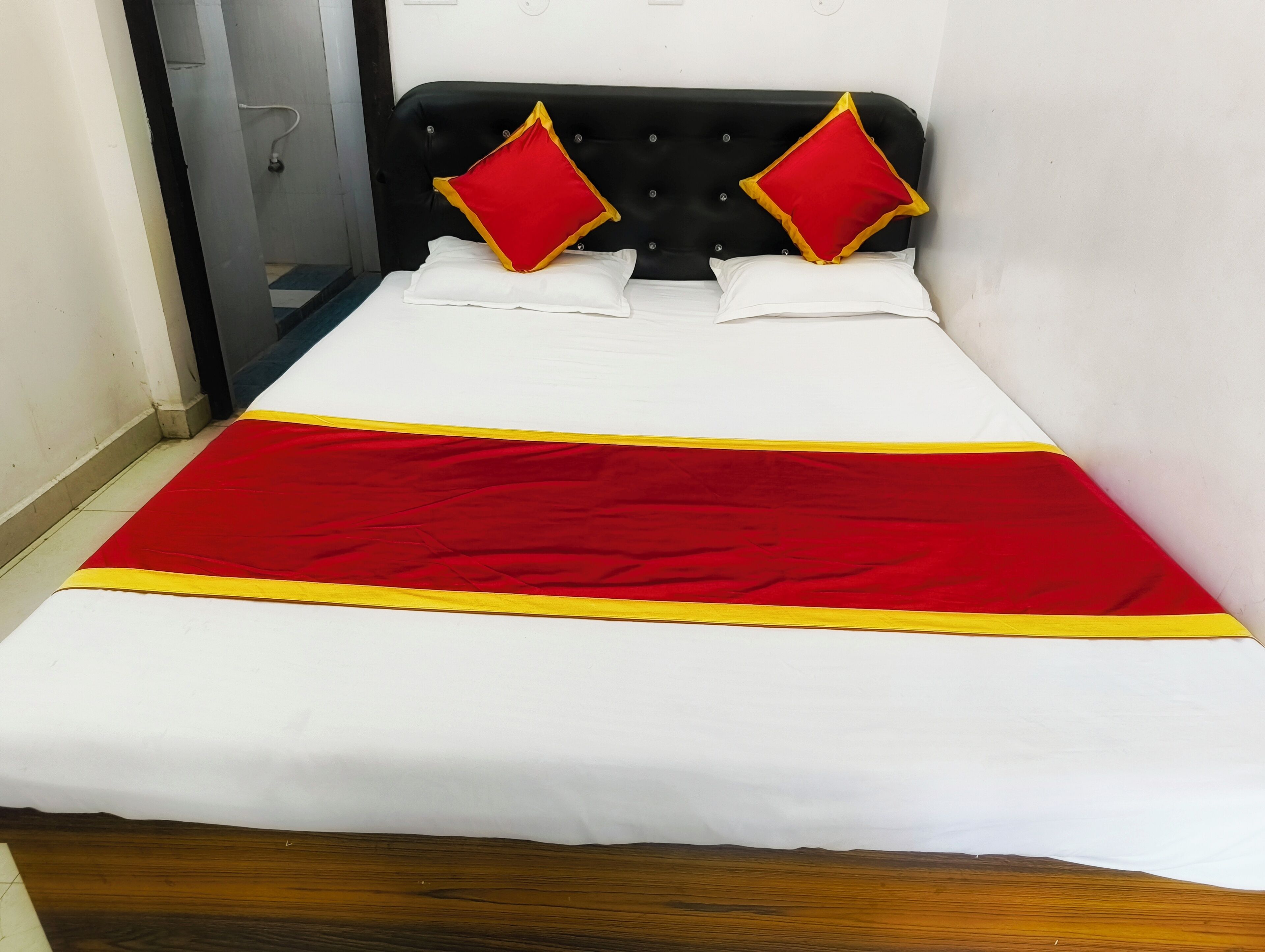 A bed with a white and red bedspread, two red pillows, and a black headboard.