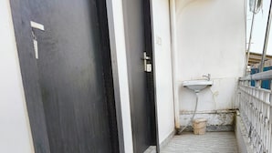 A narrow corridor with marble flooring, a black door, and a white sink with a hose. - Hotel Dream  (Patna)