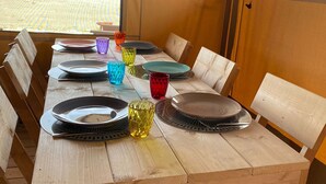 Una mesa de madera preparada para comer, con platos, vasos y cubiertos.