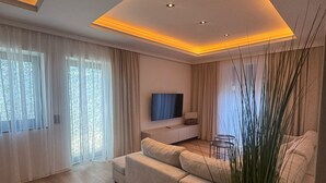 A modern living room with a sofa, a TV, and a dining area.