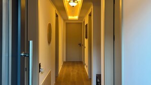 A hallway with a wooden floor, white walls, and doors on both sides.