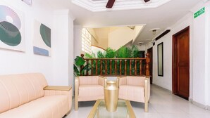 A reception area with a sofa, a coffee table, and a staircase with plants. - Hotel Med Cartagena (Cartagena)
