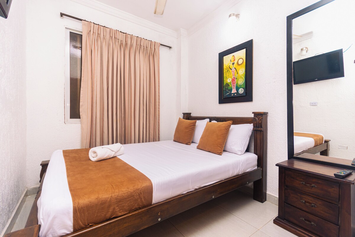 A bedroom with a bed, a dresser, a mirror, and a painting on the wall.