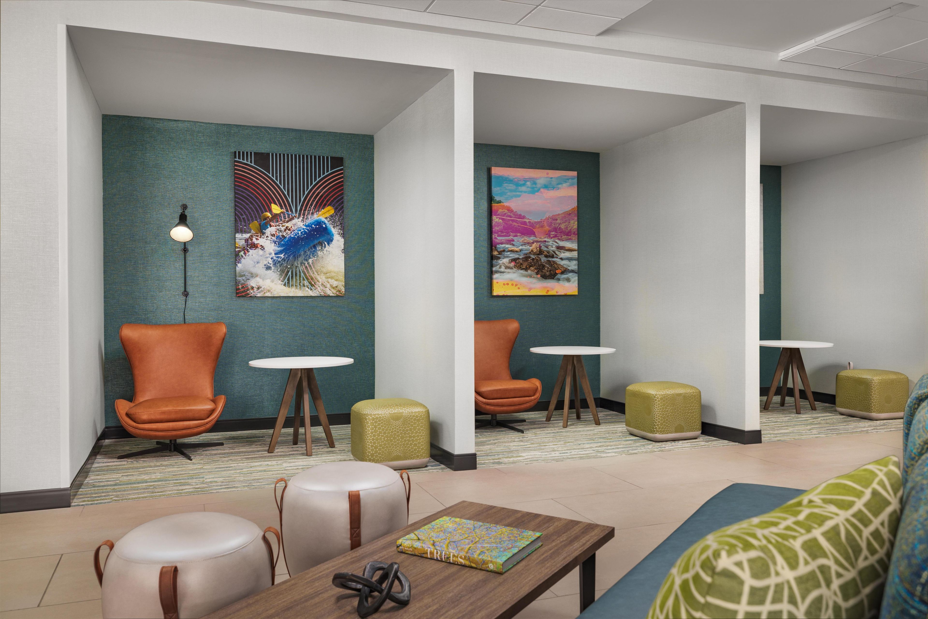Un hall d’hôtel moderne, doté d’espaces aménagés avec des sièges, d’œuvres d’art aux murs et d’une table basse sur laquelle est posé un livre.