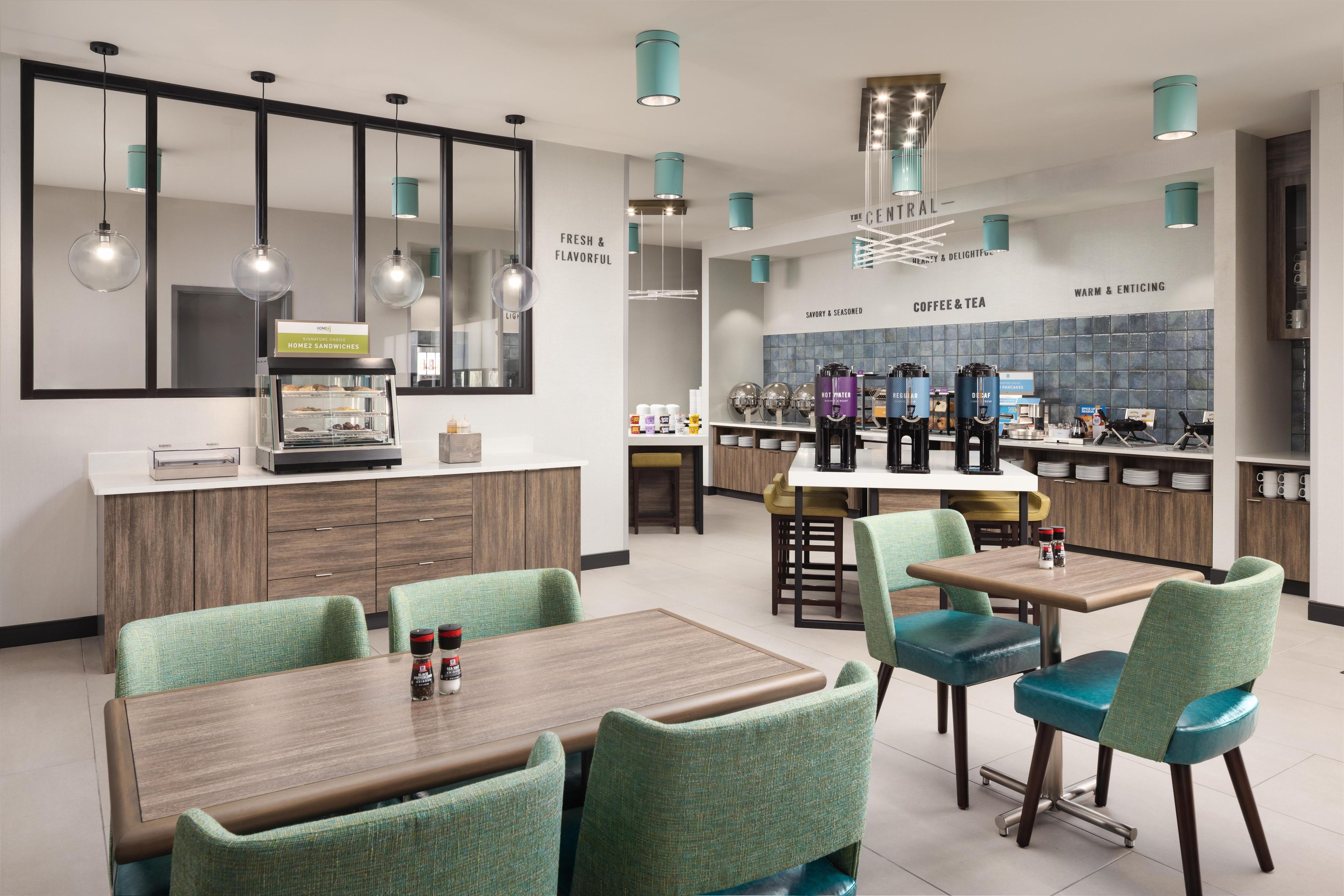 A modern cafe with a central counter, seating area, and coffee machines.