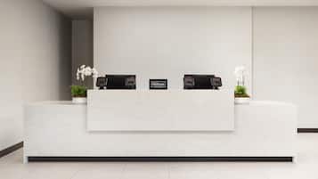 A clean, modern reception desk with two phones, a sign reading "Hilton Honors," and potted plants.