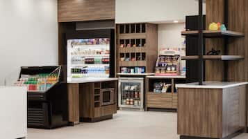 Ein moderner Verkaufsraum mit Kühlregalen, einem Getränkeautomaten und Regalen voller Snacks und Getränke.
