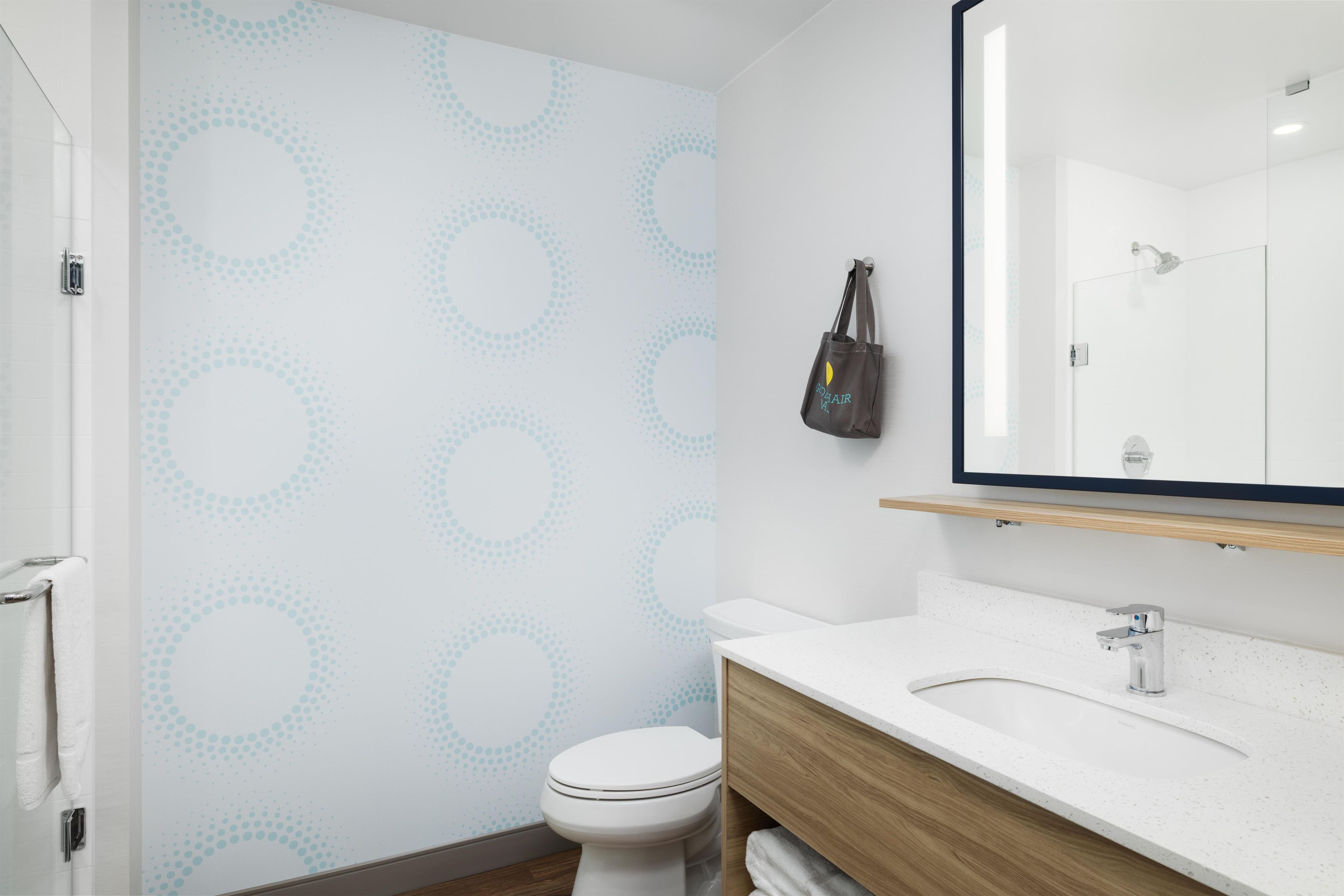 Een badkamer met toilet, wastafel, spiegel en handdoekrek.