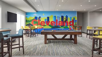 Ein Billardtisch in einem Raum mit Wandgemälde einer Stadtansicht und dem Schriftzug 'Cleveland' an der Wand.