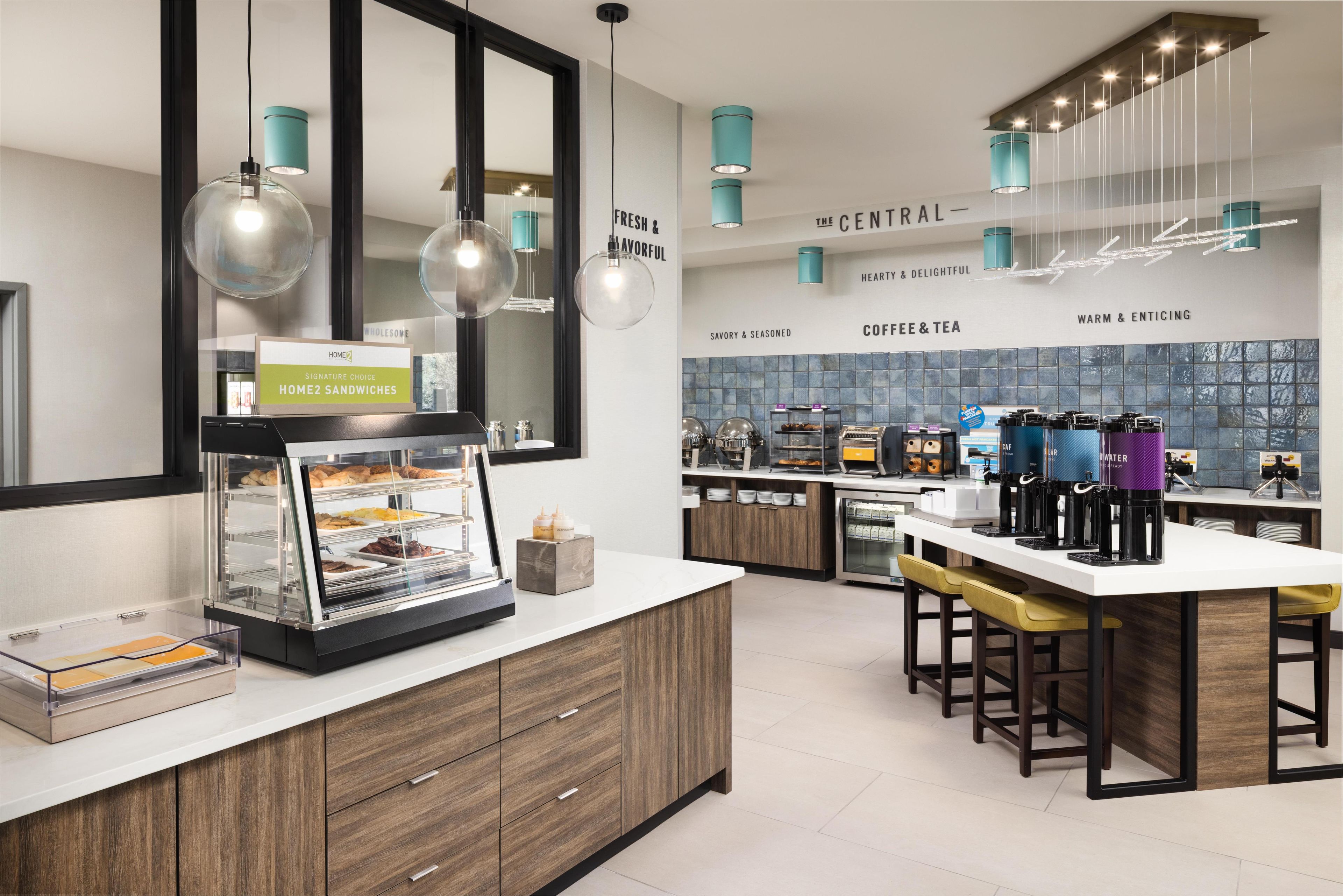 A modern kitchen with a central island, bar stools, and a coffee station.