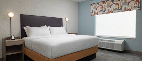 A modern hotel room with a bed, nightstands, a window, and a radiator.