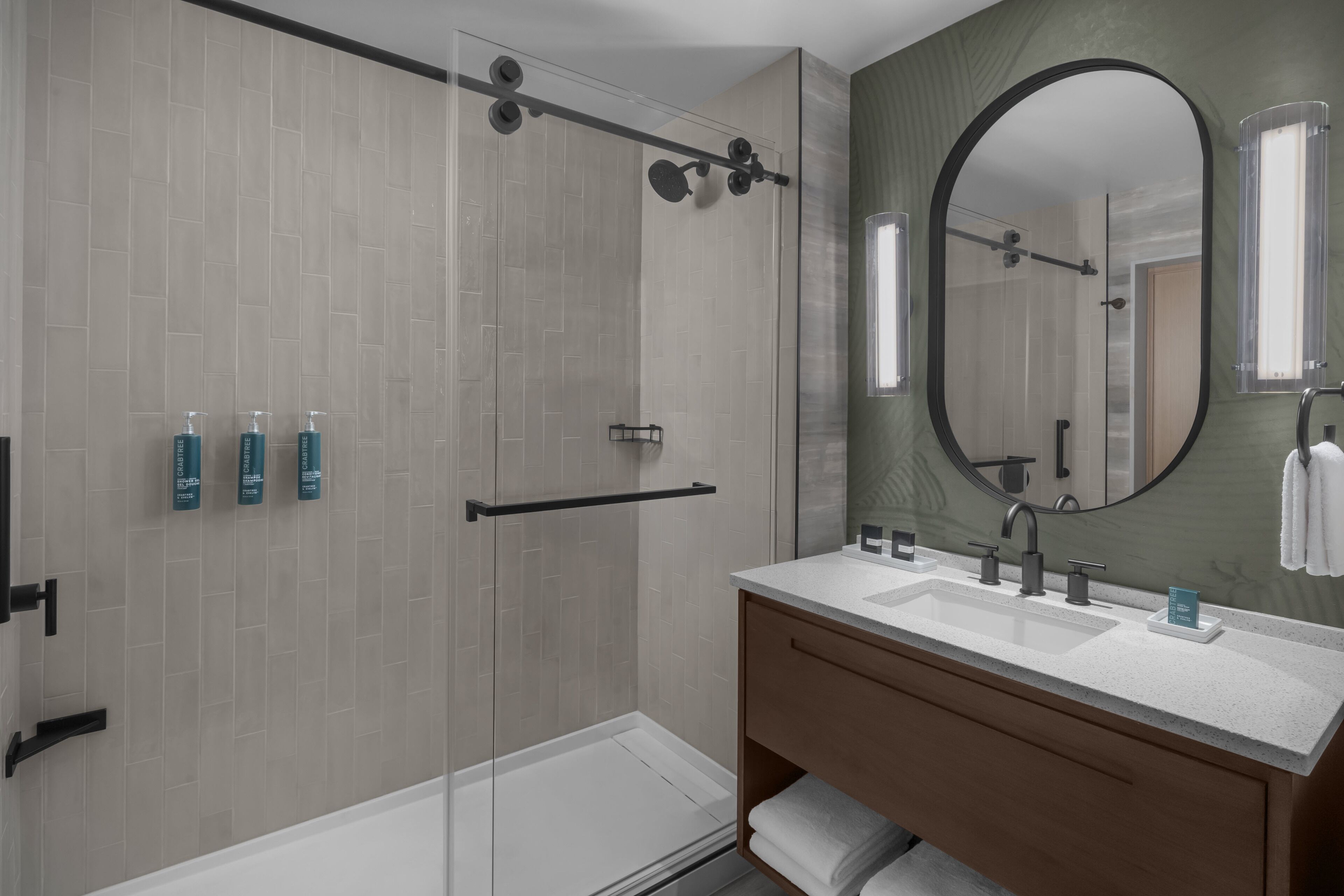 A modern bathroom with a glass-enclosed shower, a large mirror, and a vanity with a sink.