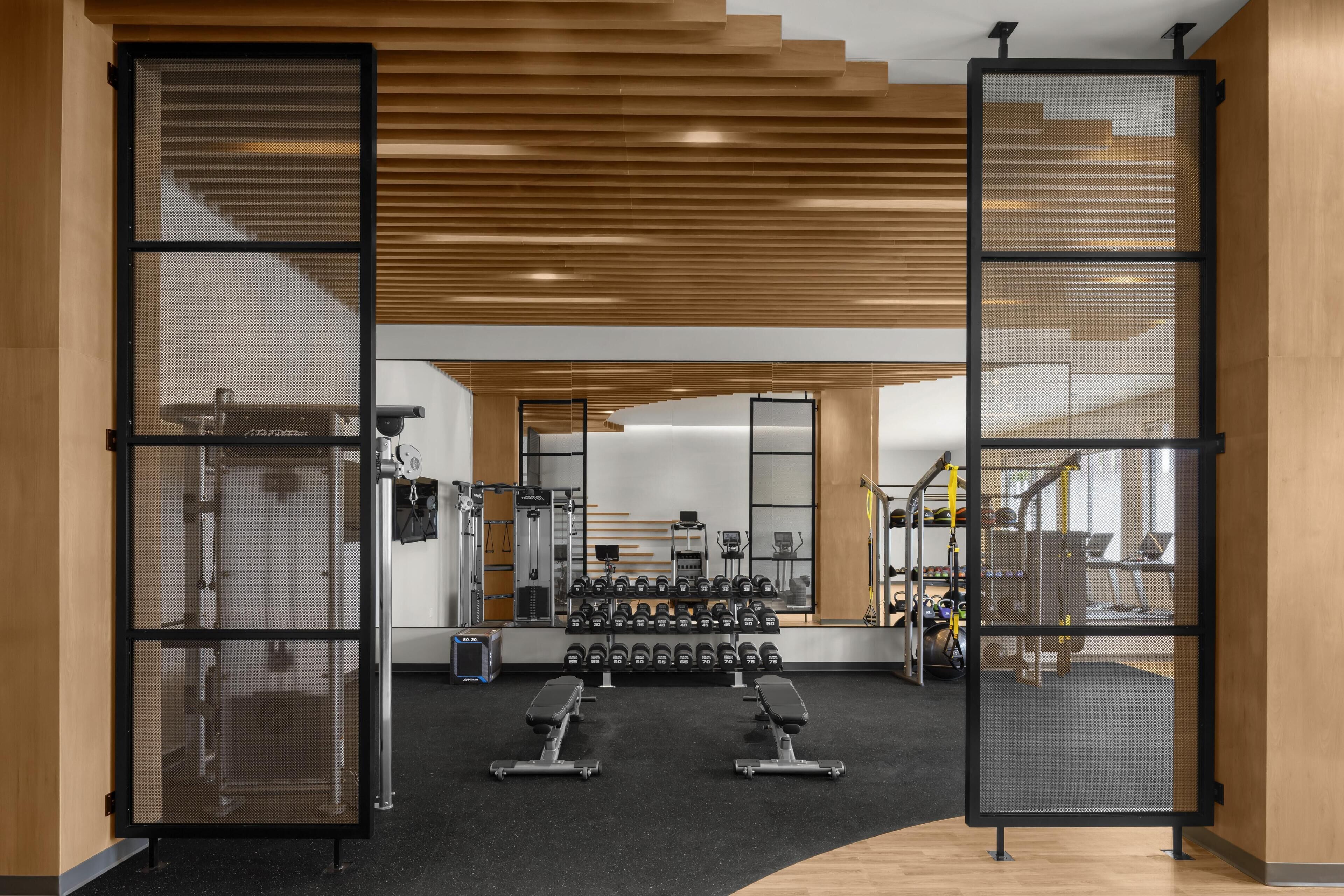 Une salle de sport moderne équipée de supports à poids, d’haltères et d’appareils d’exercice.