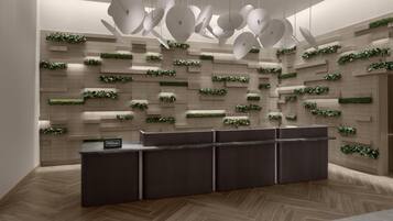 A modern hotel reception area with a dark reception desk, a wall-mounted plant display, and a unique ceiling light fixture.