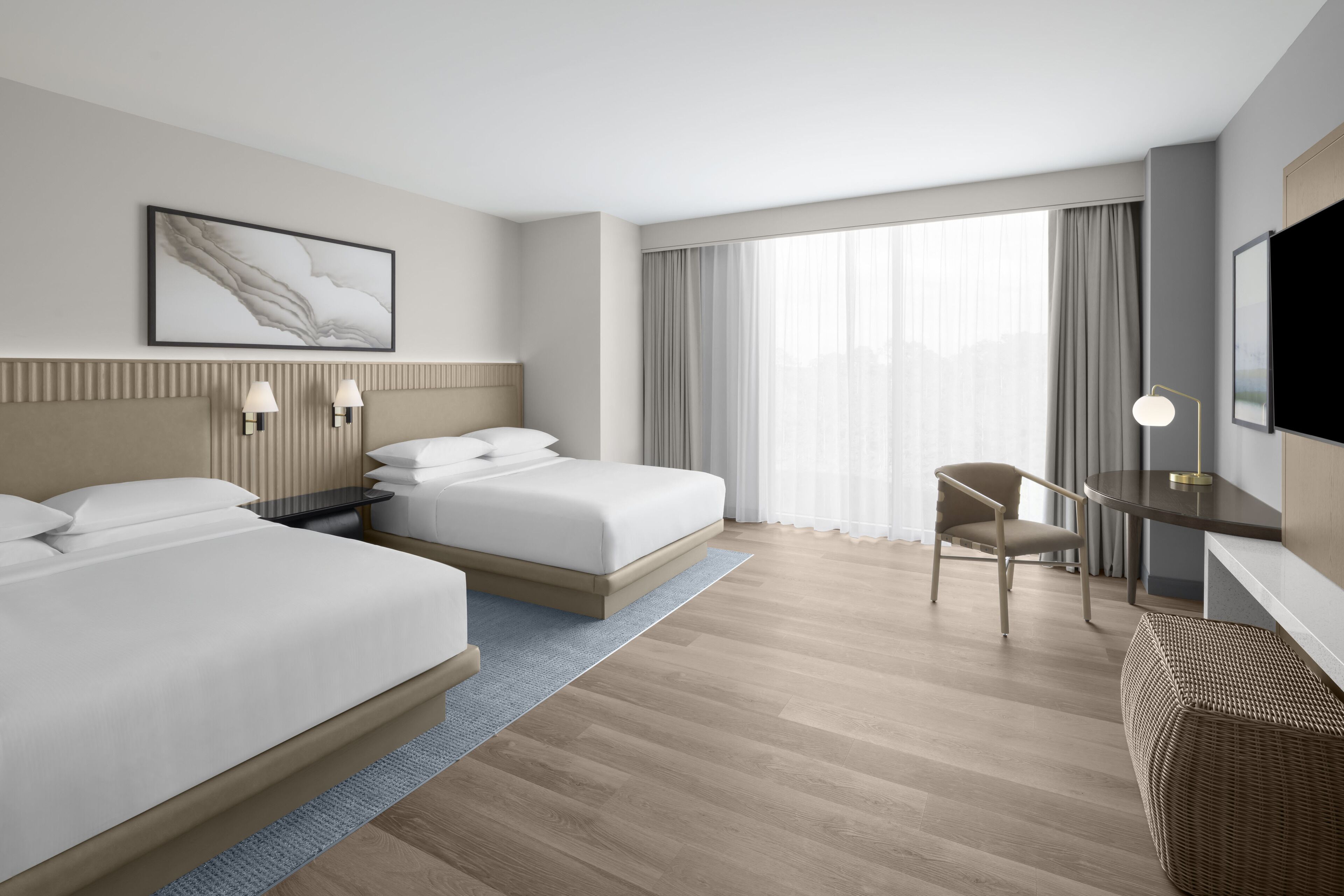 Une chambre d’hôtel moderne équipée de deux lits, d’un bureau, d’une chaise et d’un téléviseur.