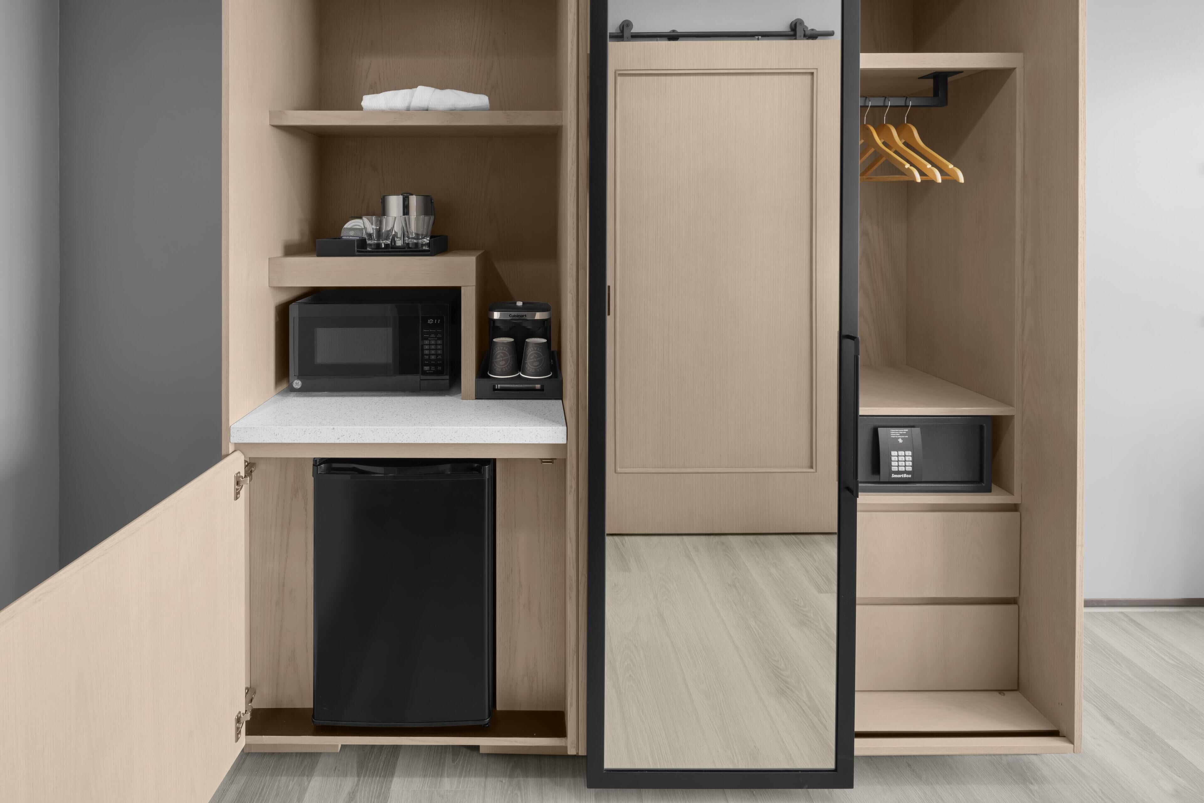 Una kitchenette compacta equipada con microondas, cafetera y refrigerador pequeño.